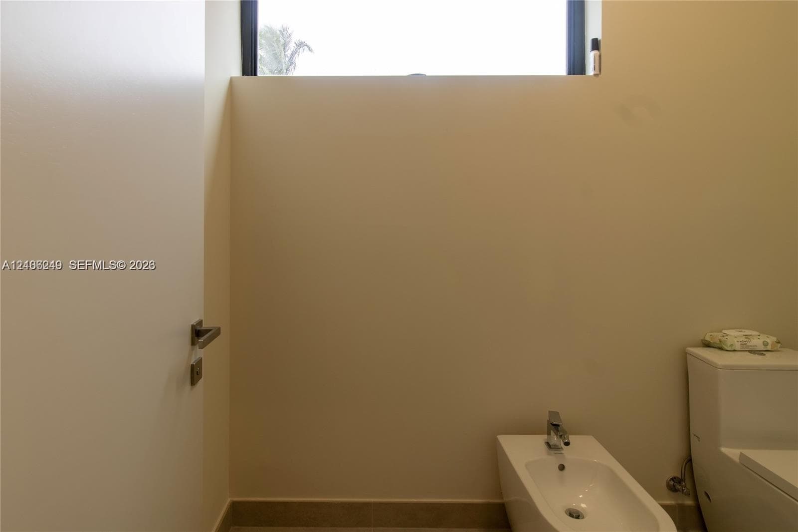 High-ceiling space featuring a clerestory window, white porcelain bidet with a chrome faucet, and a dual-flush toilet