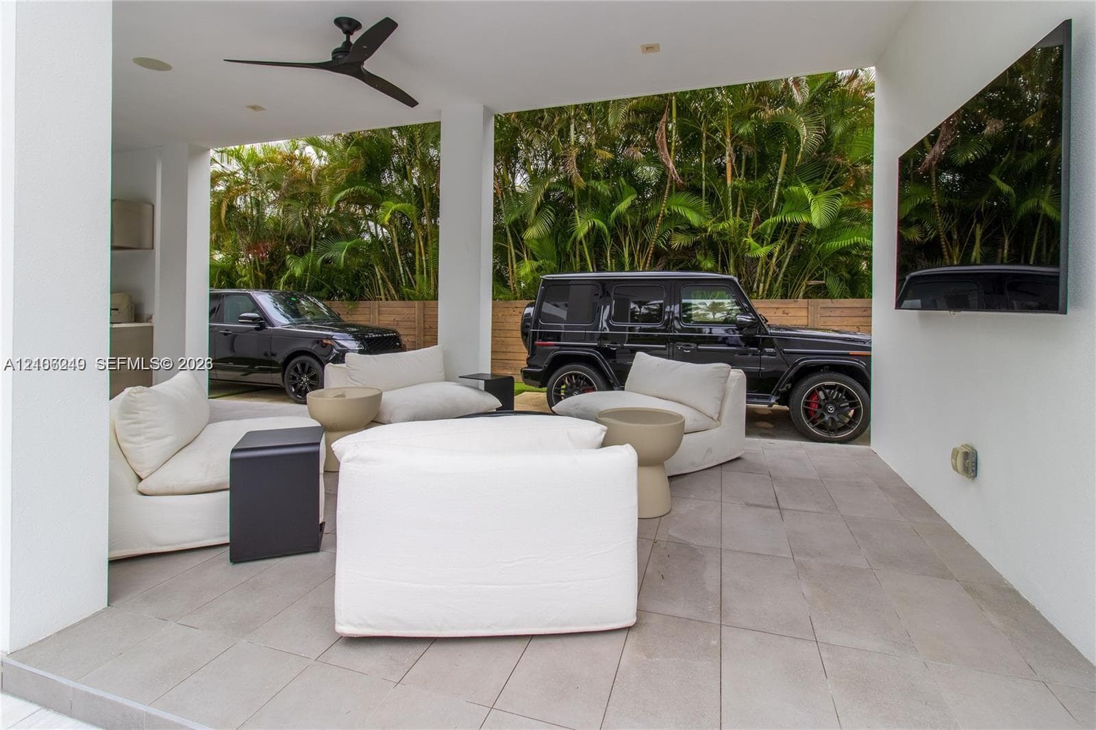 Covered outdoor space featuring large-format tile flooring, recessed lighting, a matte black ceiling fan, and wall-mounted television interface