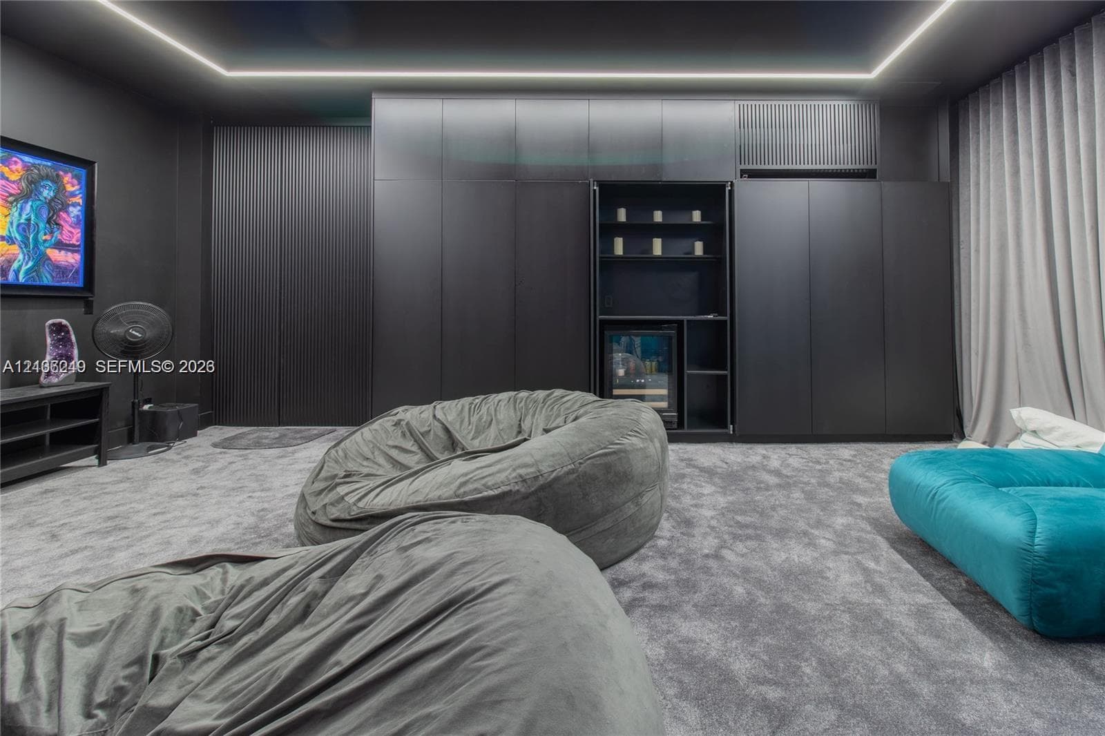 Floor-to-ceiling matte black cabinetry, integrated shelving unit with a built-in beverage refrigerator, cove ceiling lighting, and wall-to-wall carpeting
