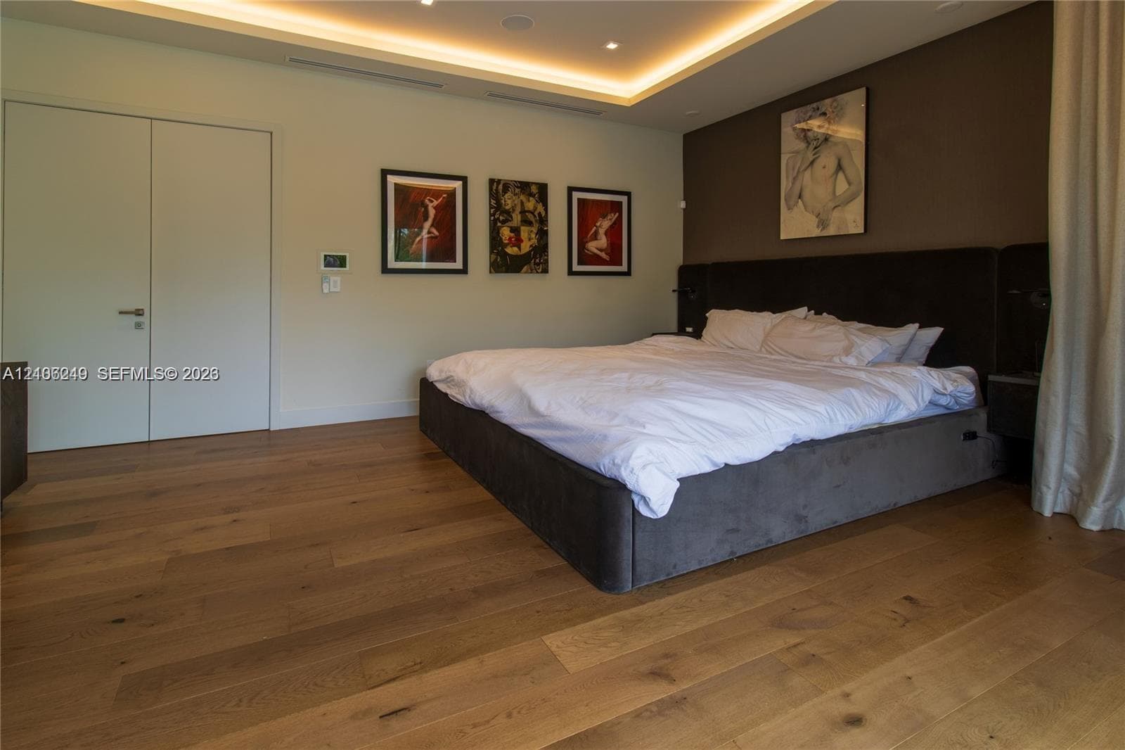 Tray ceiling with integrated recessed lighting, wood-finish flooring, and solid-core doors