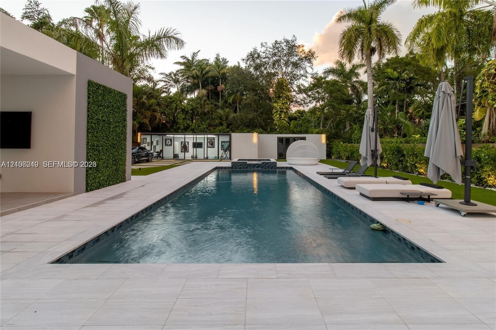 Rectangular swimming pool with integrated spa, light-toned stone pool deck, and vertical green wall feature