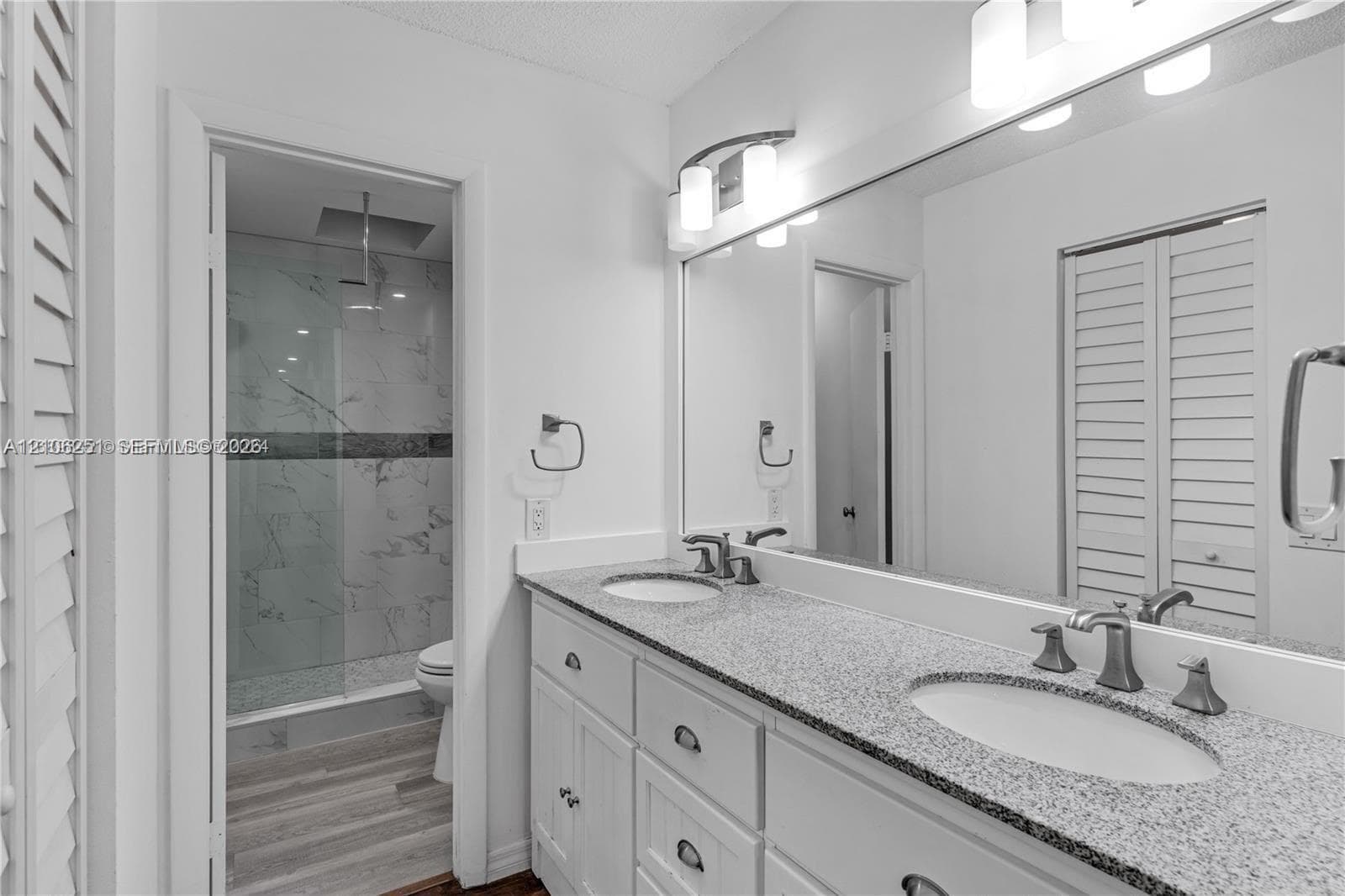 Double vanity featuring a speckled countertop, integrated dual sinks, and brushed metallic hardware