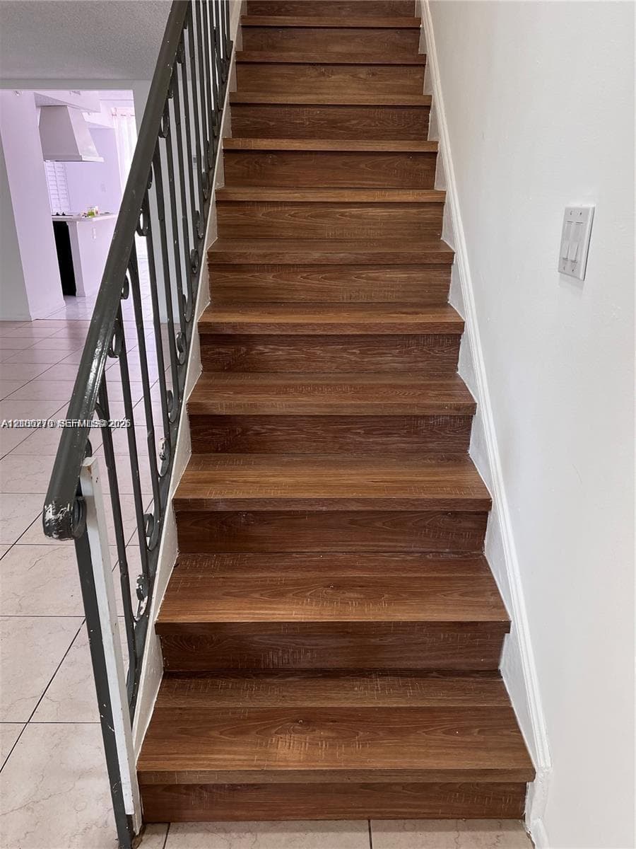 Staircase featuring wood-finish treads and a decorative metal railing