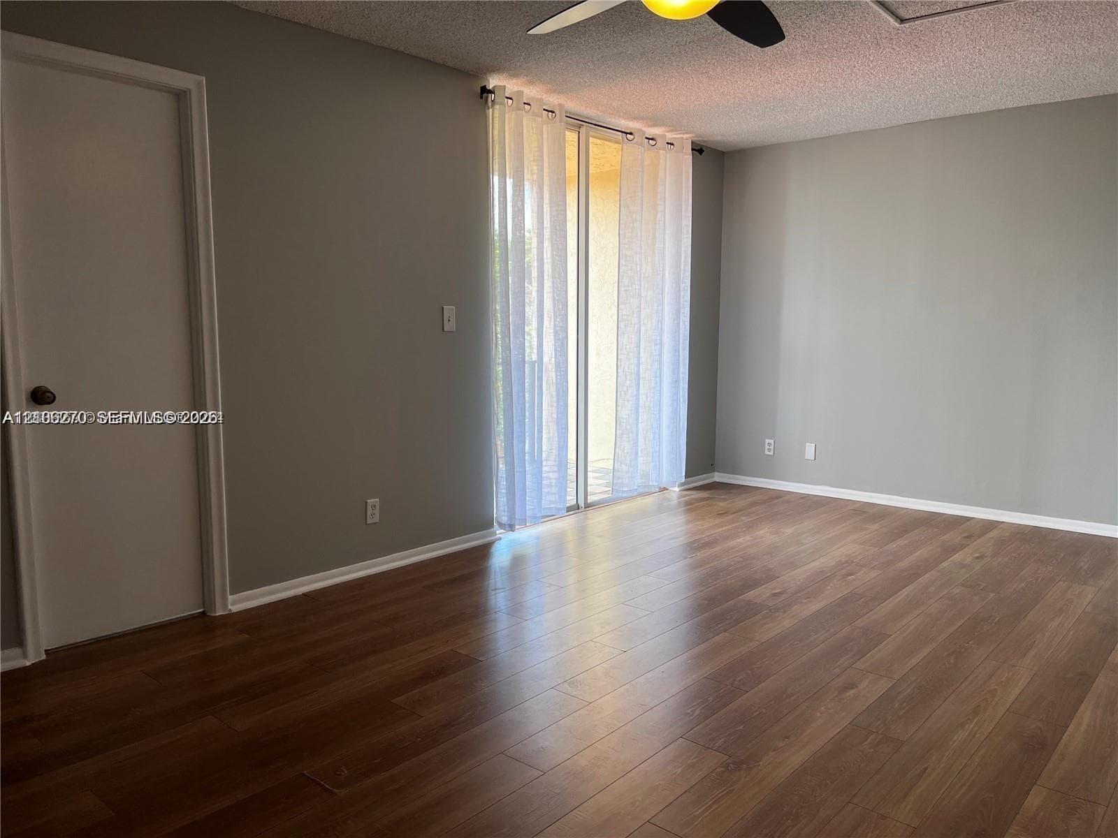 Interior space featuring wood-finish flooring, sliding glass door, and a ceiling fan with integrated lighting