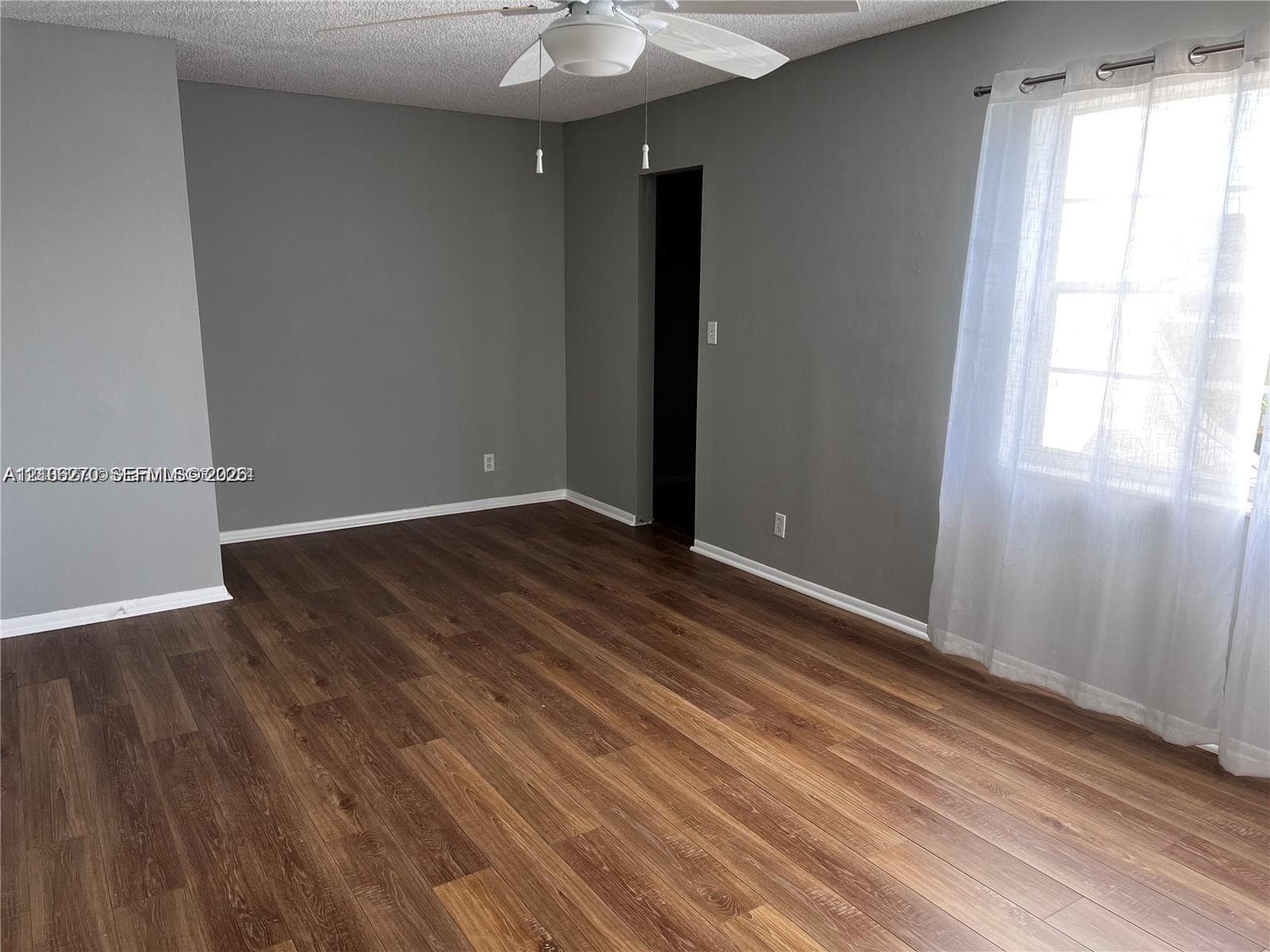 Room featuring wood-finish flooring, neutral-toned walls, and a ceiling fan with integrated lighting