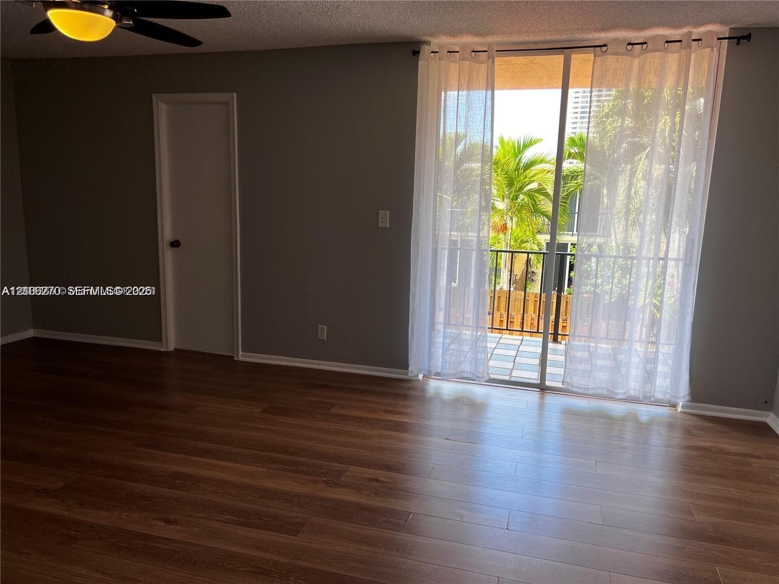 Wood-finish flooring, sliding glass balcony door, metal balcony railing, and ceiling-mounted fan with integrated lighting