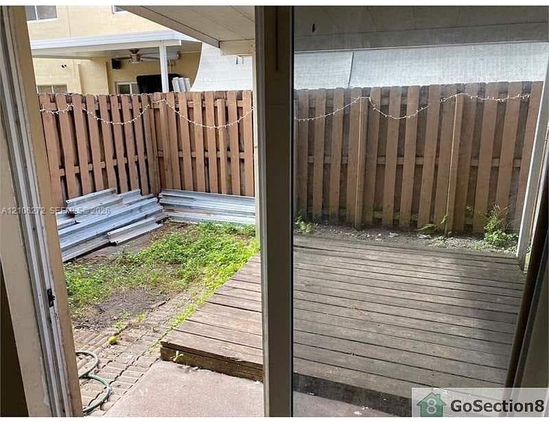 Private outdoor patio featuring a wood-plank deck, concrete paver accents, and a perimeter wood-slat privacy fence