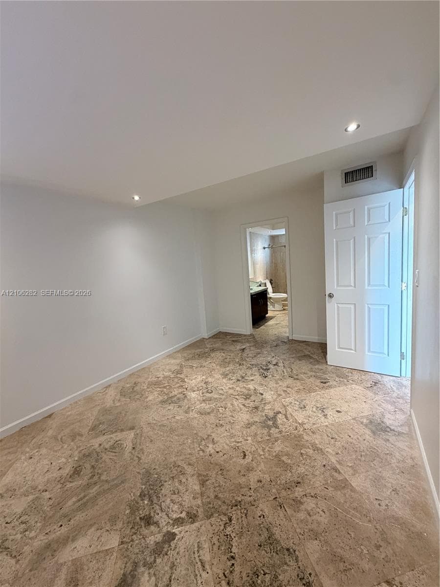 Stone tile flooring featuring a natural texture, recessed ceiling lighting, and a multi-panel interior door
