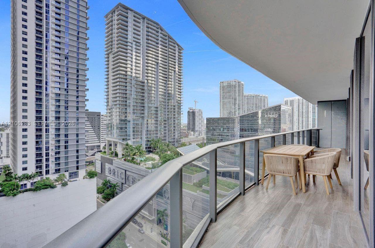 Covered balcony featuring wood-finish flooring and a glass-paneled metal railing