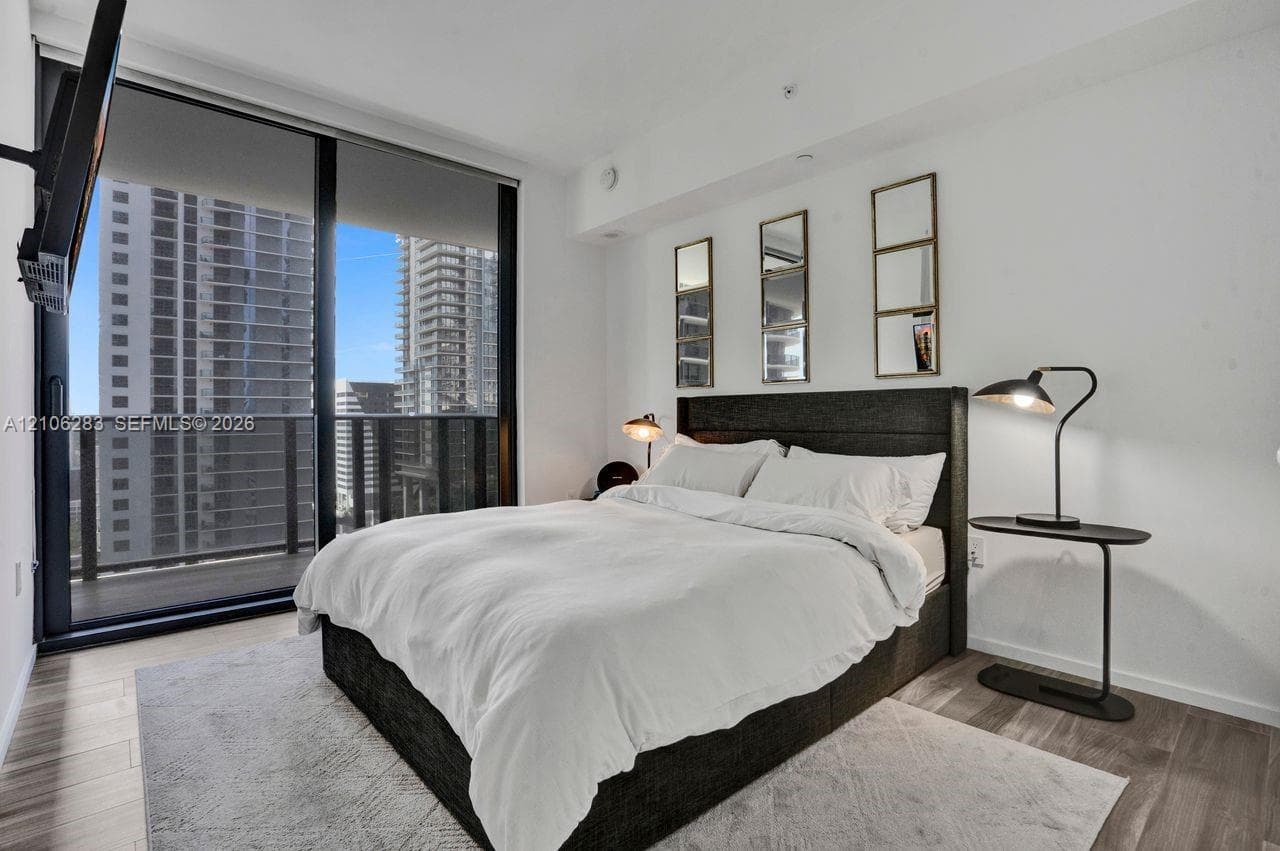 Floor-to-ceiling glass sliding door, integrated private balcony, wood-finish flooring, and neutral wall palette