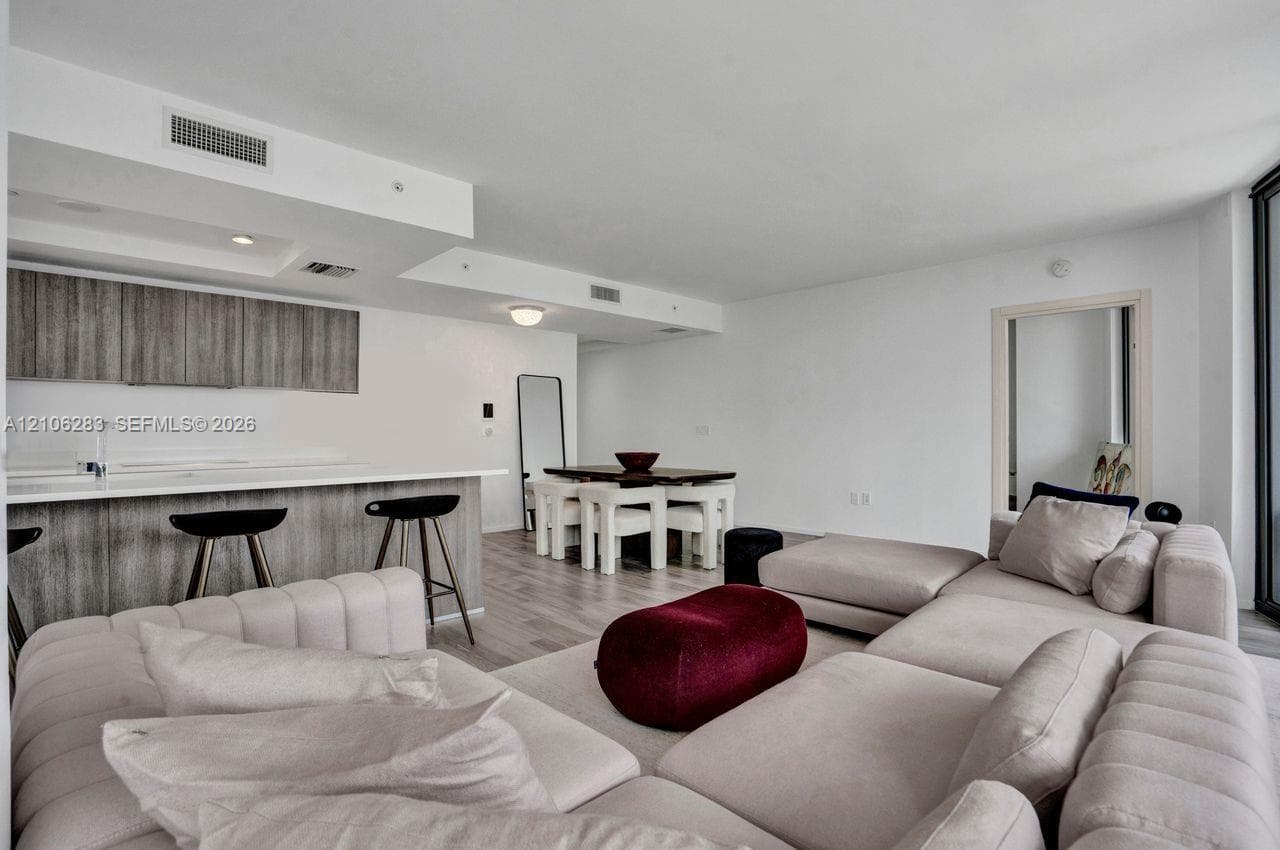 Open-concept interior featuring light wood-finish flooring, recessed lighting, and a kitchen equipped with flat-panel cabinetry and a solid-surface breakfast bar