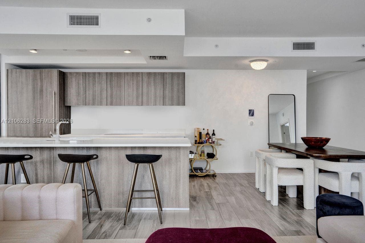 Kitchen featuring wood-finish cabinetry, a white countertop island, integrated lighting, and wood-finish flooring