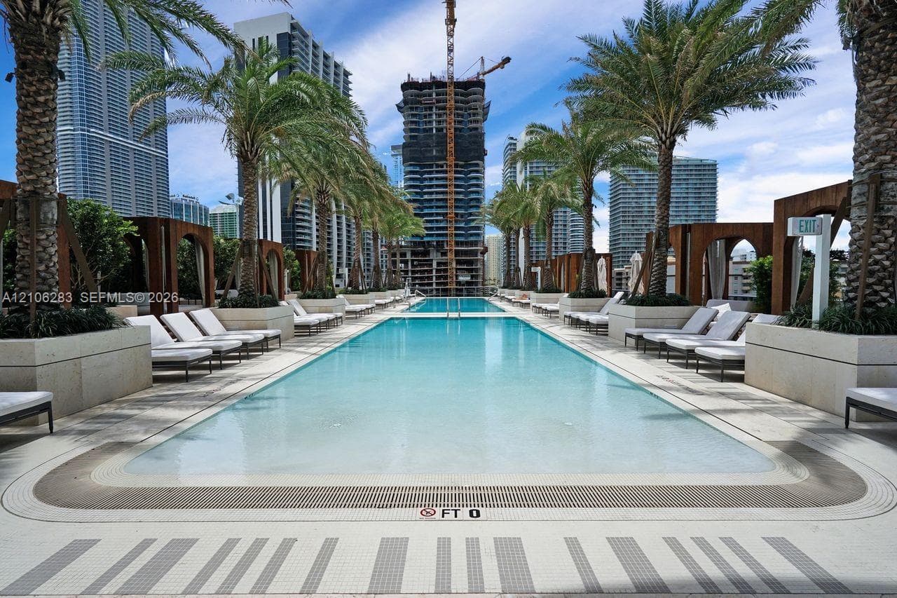 Rectangular swimming pool featuring stone-tile decking, built-in wooden cabanas, mature palm trees, and integrated landscaping planters