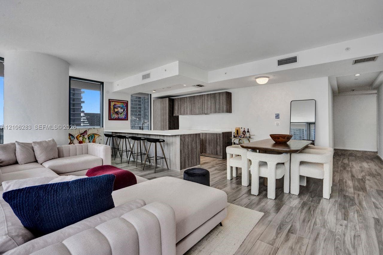 Open-concept interior featuring wood-finish flooring, a kitchen island with stone countertop, and custom-finish cabinetry