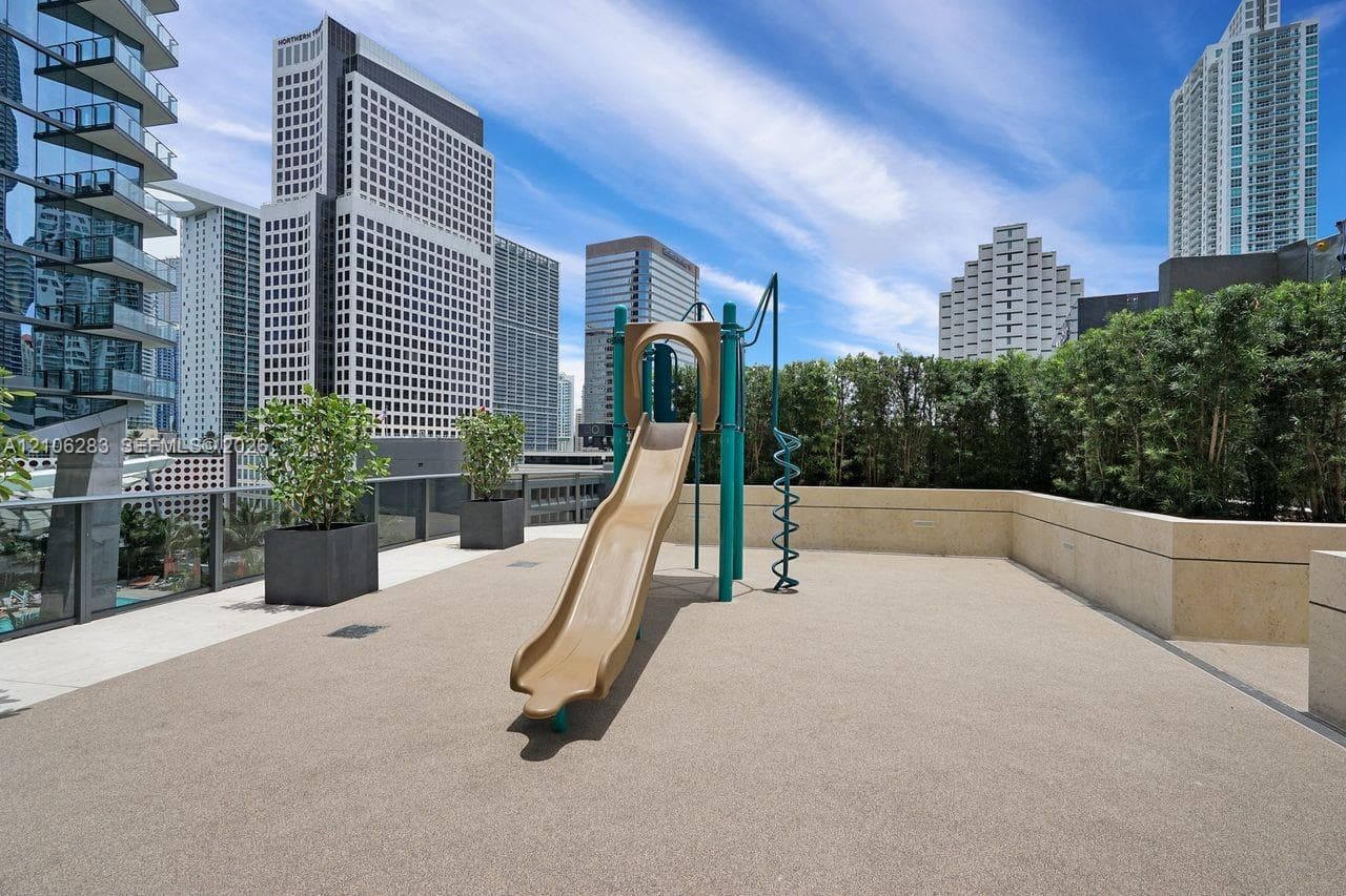 Outdoor terrace featuring a built-in playground slide, stone-finish flooring, masonry perimeter walls, and large container planters