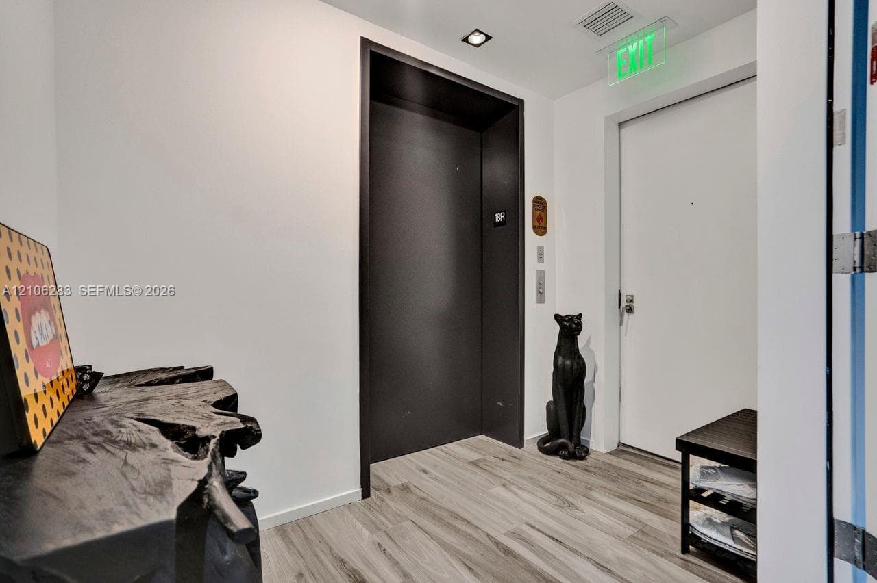Entrance featuring wood-finish flooring, a matte black elevator door, and recessed ceiling lighting