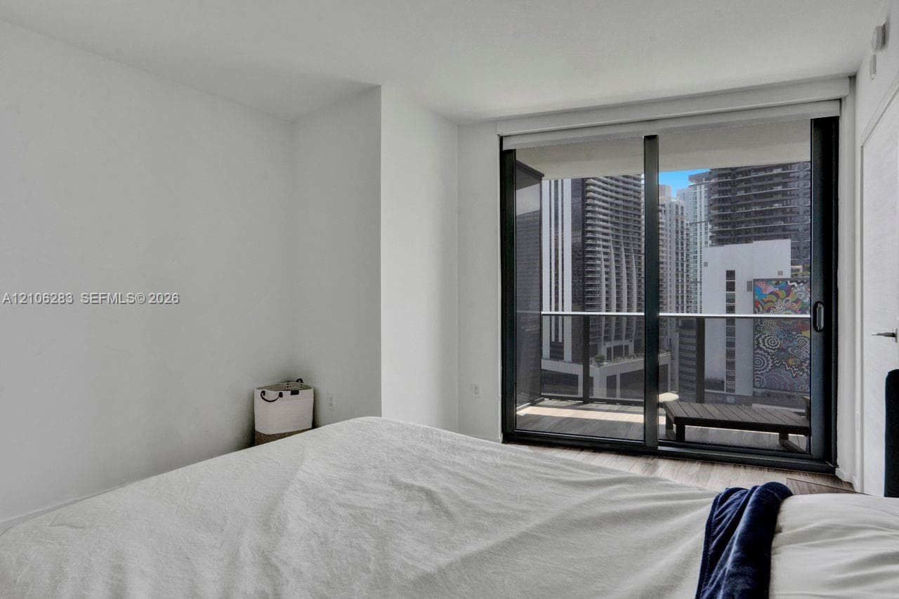 Floor-to-ceiling sliding glass door, private balcony with metal railing, and wood-finish flooring