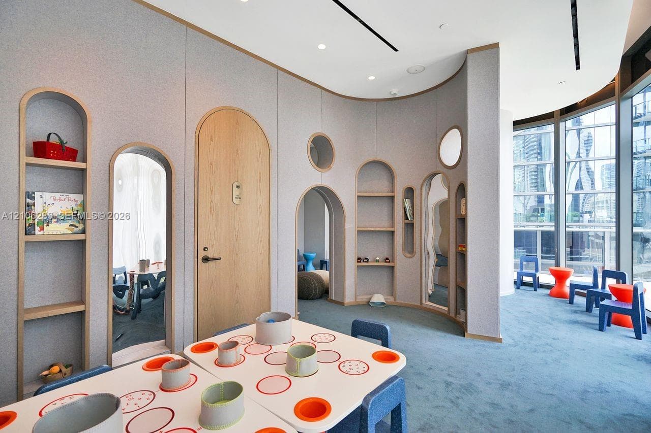 Curved wall paneling featuring integrated arched shelving, wood-finish arched doorways, floor-to-ceiling windows, and recessed ceiling lighting