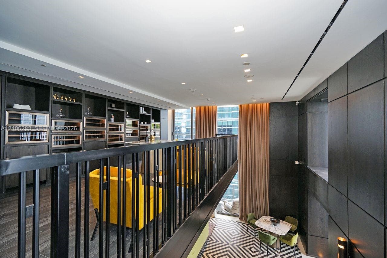 Custom built-in cabinetry featuring integrated temperature-controlled storage, dark wood-finish wall paneling, metal railing, and recessed ceiling lighting