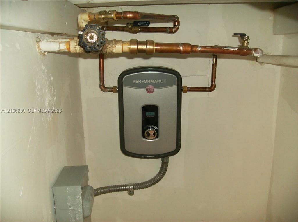 Tankless electric water heater featuring digital temperature controls, copper plumbing lines, and a shut-off valve
