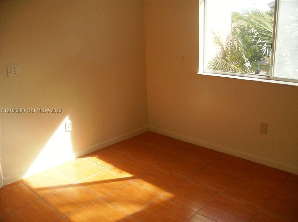 Ceramic tile flooring, neutral wall finishes, and a sliding window featuring natural exterior greenery