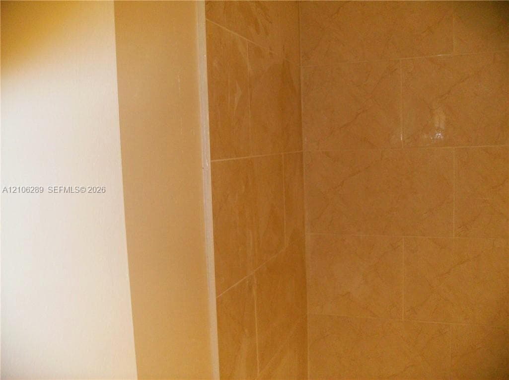 Neutral-toned wall finish with floor-to-ceiling tile surround featuring a subtle textured pattern