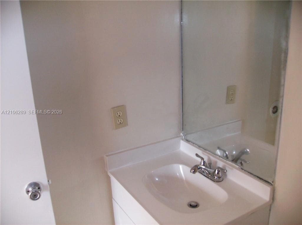 Vanity featuring a seamless integrated countertop and sink, polished chrome dual-handle faucet, and wall-mounted mirror