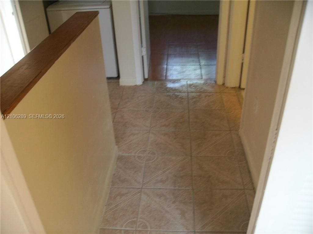 Square-tile flooring with textured detail, complemented by a half-wall featuring a stained wood cap