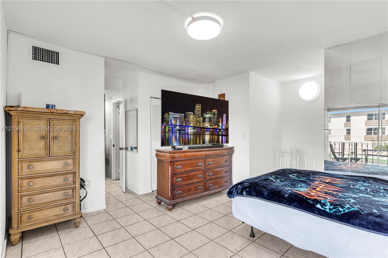 Tiled flooring, mirrored wall paneling, circular wall-mounted lighting, and flush-mount ceiling fixture