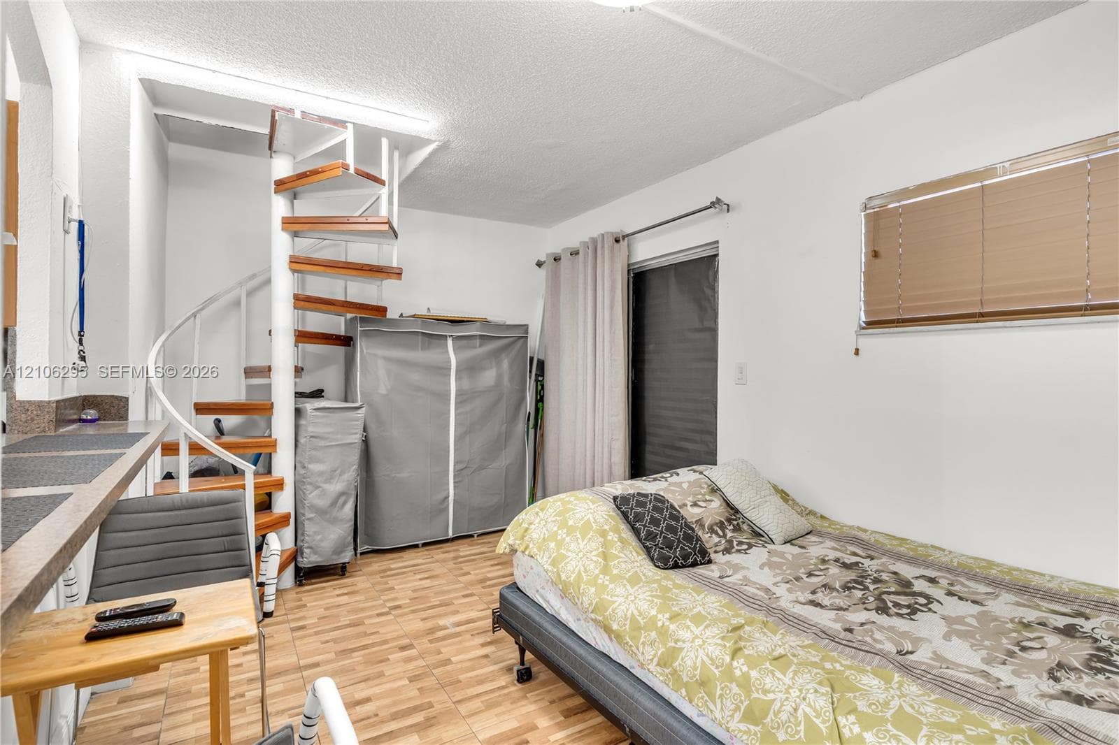 Spiral staircase with wood treads and metal railing, wood-finish flooring, and horizontal window blinds