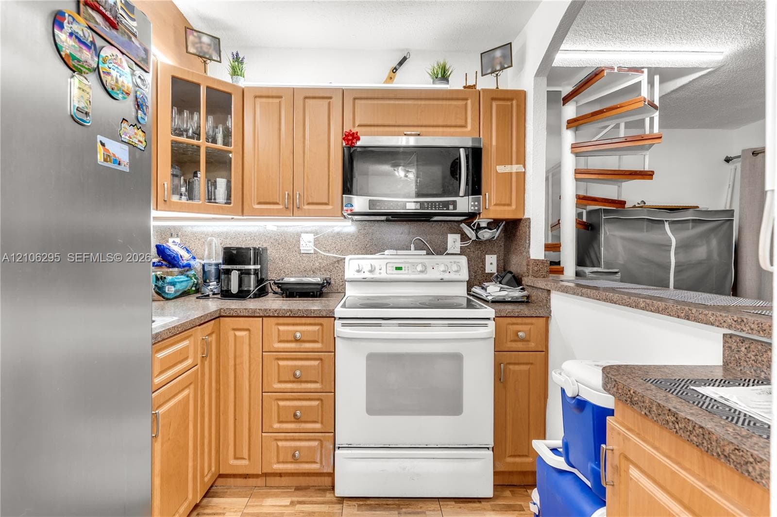 Kitchen featuring medium-tone wood cabinetry, built-in microwave, integrated stainless steel range, stone-composite countertops, and a decorative spiral staircase