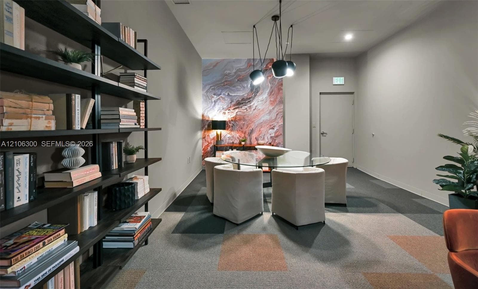 Floor-to-ceiling built-in black metal shelving unit, geometric patterned modular carpeting, decorative marble-finish accent wall, and multi-pendant modern light fixture