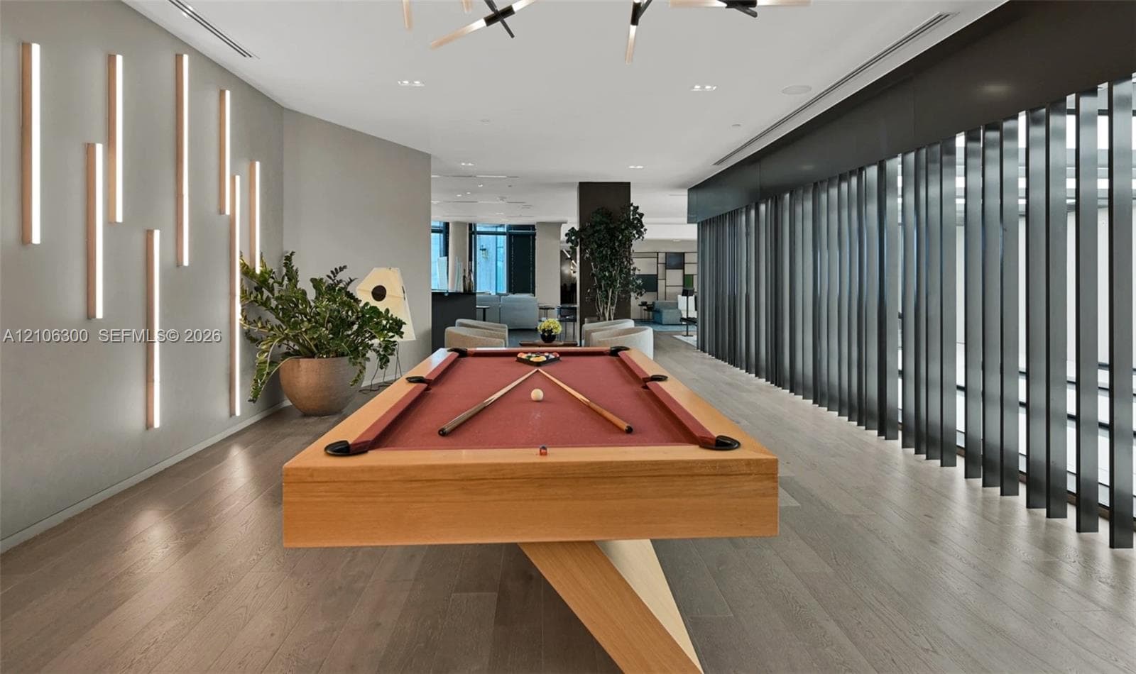 Open-concept recreational space featuring wood-finish flooring, vertical wall-mounted accent lighting, and a series of floor-to-ceiling structural fins
