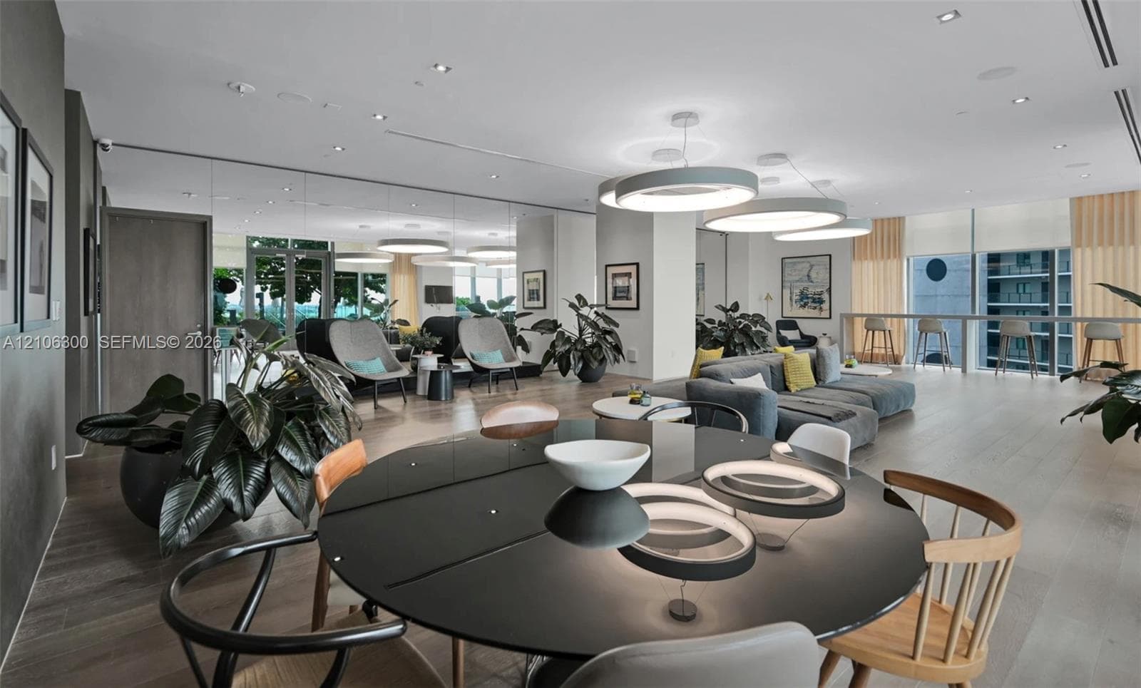 Open-concept interior featuring wood-finish flooring, recessed lighting, expansive floor-to-ceiling windows, and large circular pendant light fixtures