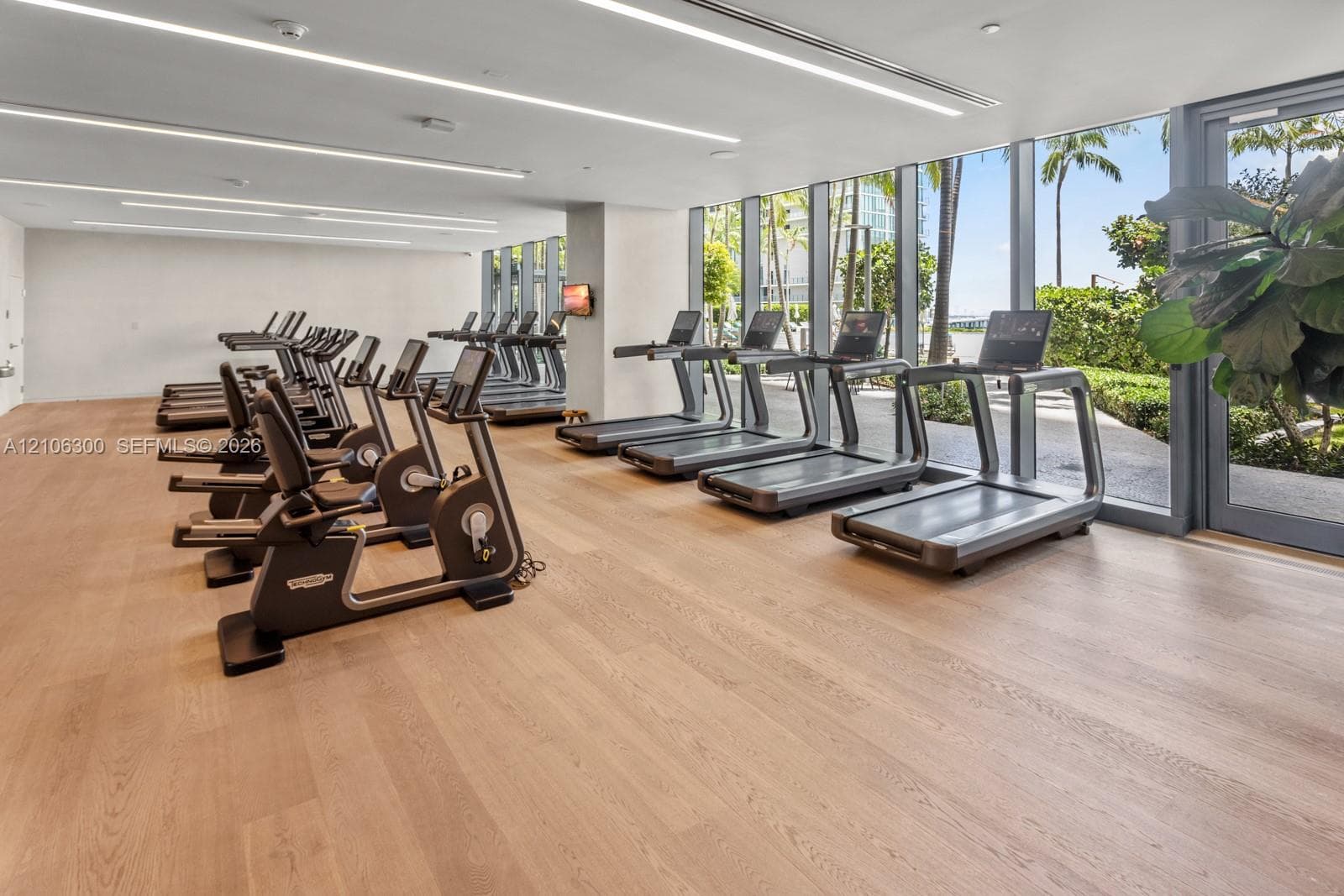Fitness center featuring wood-finish flooring, floor-to-ceiling windows, and recessed linear lighting