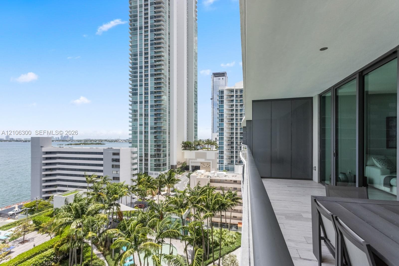 Covered balcony with stone-finish flooring, glass railing, and floor-to-ceiling glass sliding door panels