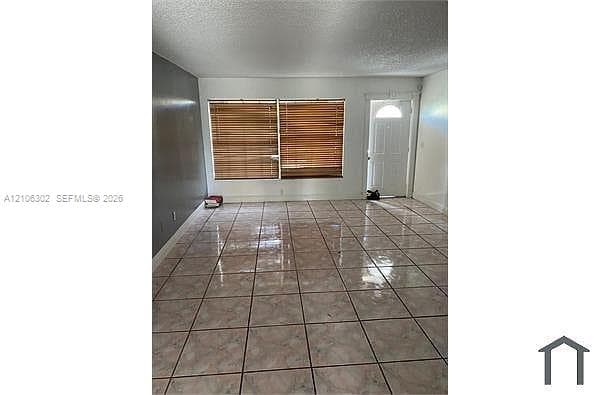 Interior space featuring large-format ceramic tile flooring, a dual-tone wall finish, and an exterior door with a semi-circular transom window