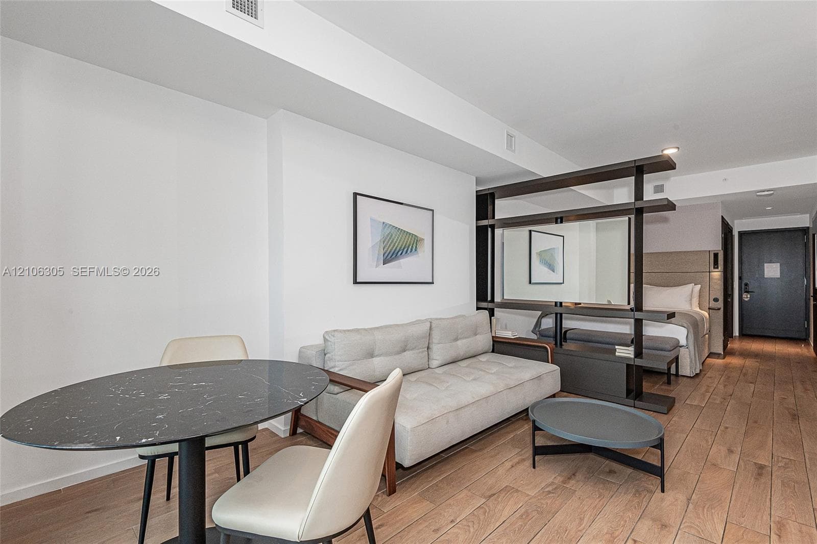 Open-concept interior featuring wood-finish flooring, a built-in dark-toned room divider, and recessed lighting