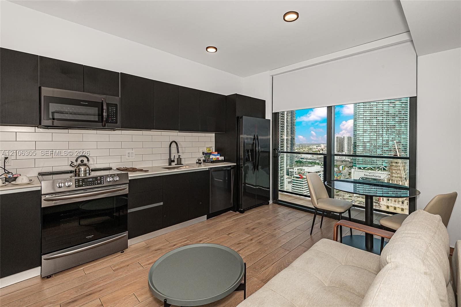 Modern kitchen featuring flat-panel cabinetry, stainless steel appliances, white subway tile backsplash, light-toned wood-finish flooring, and floor-to-ceiling windows