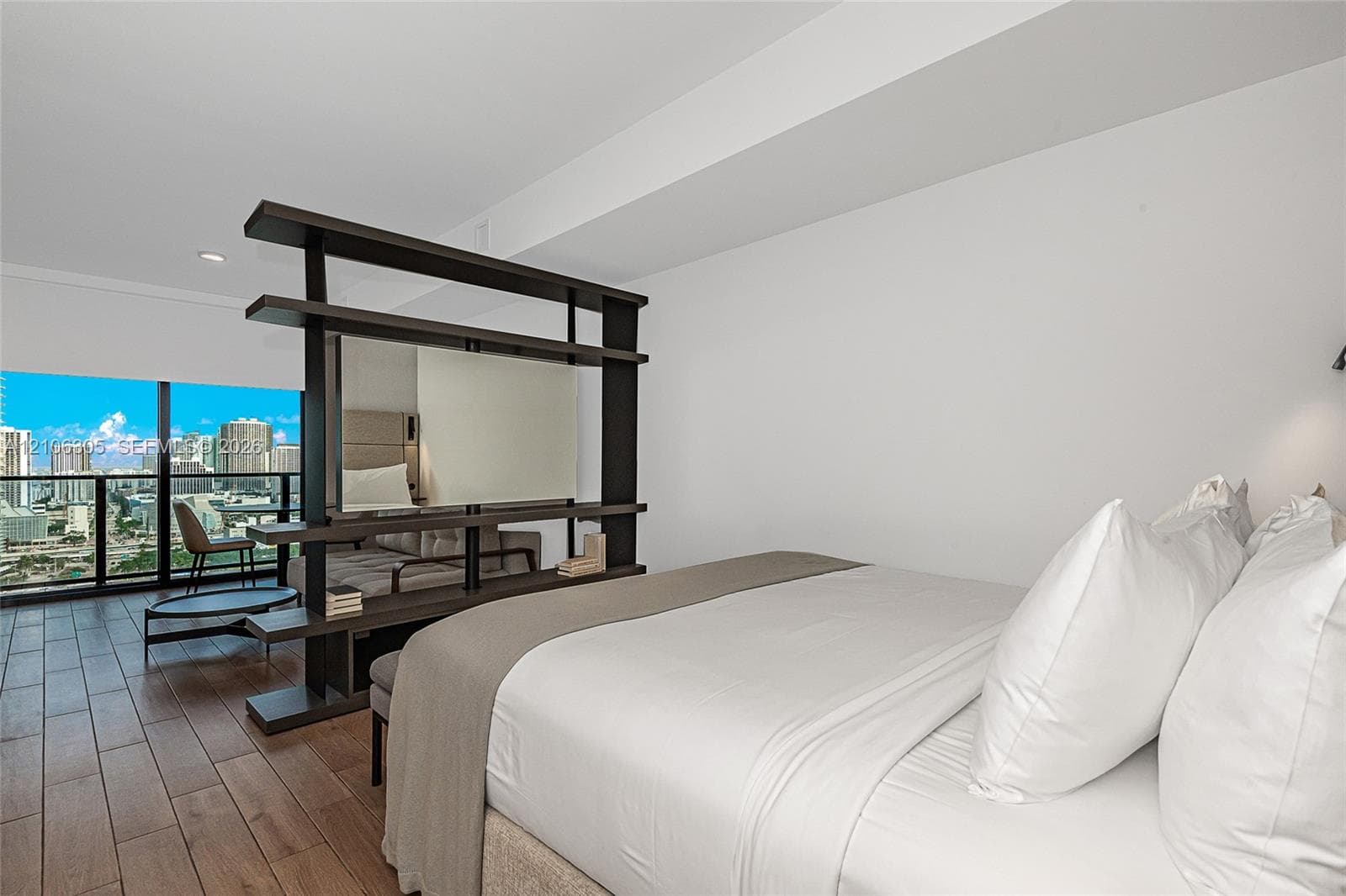 Wood-finish flooring, floor-to-ceiling windows with urban scenery, and a built-in open-shelving room divider