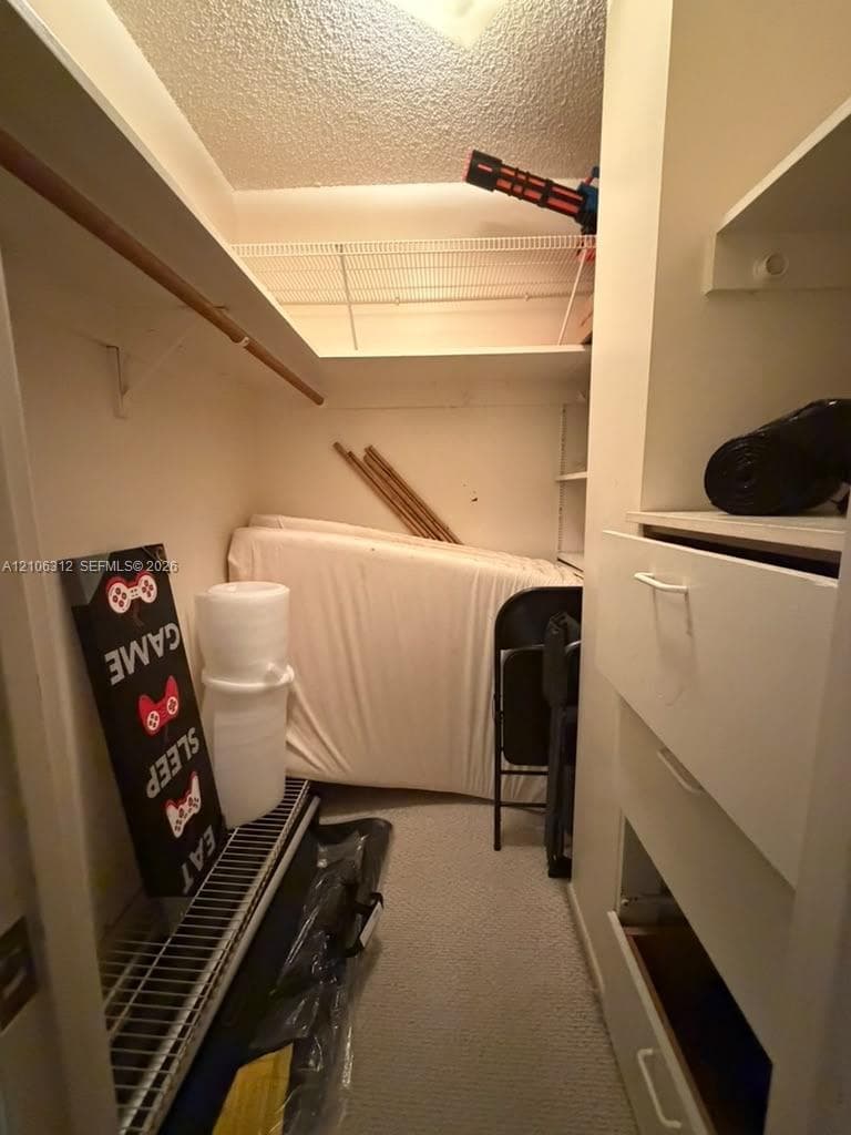 Storage area featuring built-in shelving, white integrated cabinetry with drawers, and wire rack shelving