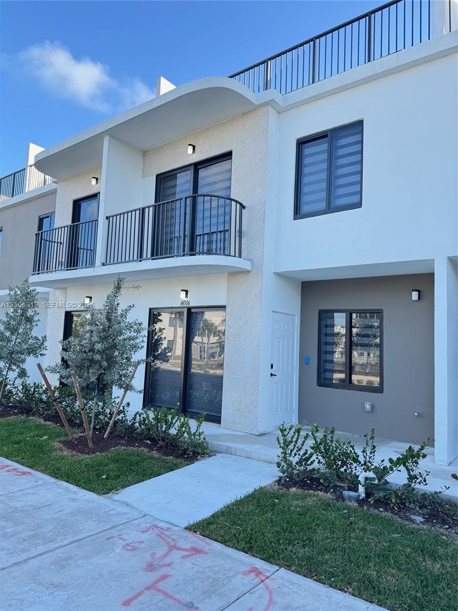 Contemporary multi-story exterior featuring a private second-level balcony with metal railing, rooftop terrace, sliding glass doors, and integrated wall-mounted lighting