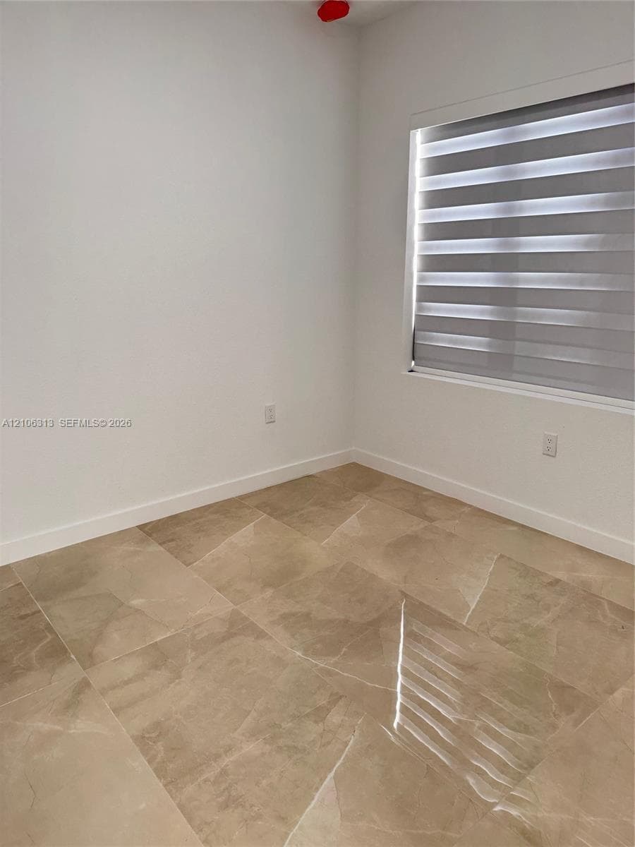 Neutral-toned large-format tile flooring, white walls, and horizontal dual-layer window treatments