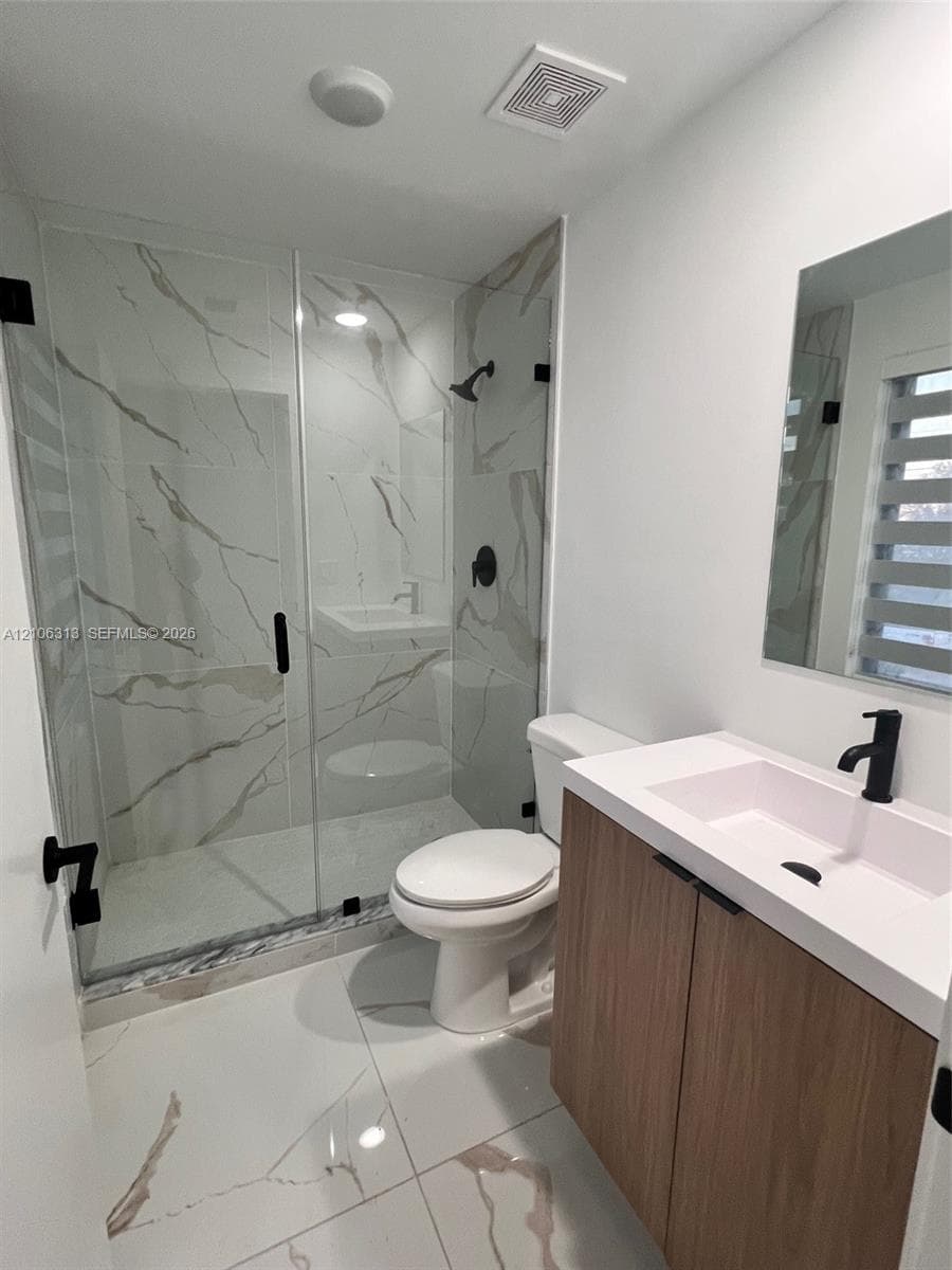 Walk-in shower featuring large-format tile surround, frameless glass enclosure, wood-finish vanity with rectangular basin, white quartz countertop, and matte black fixtures