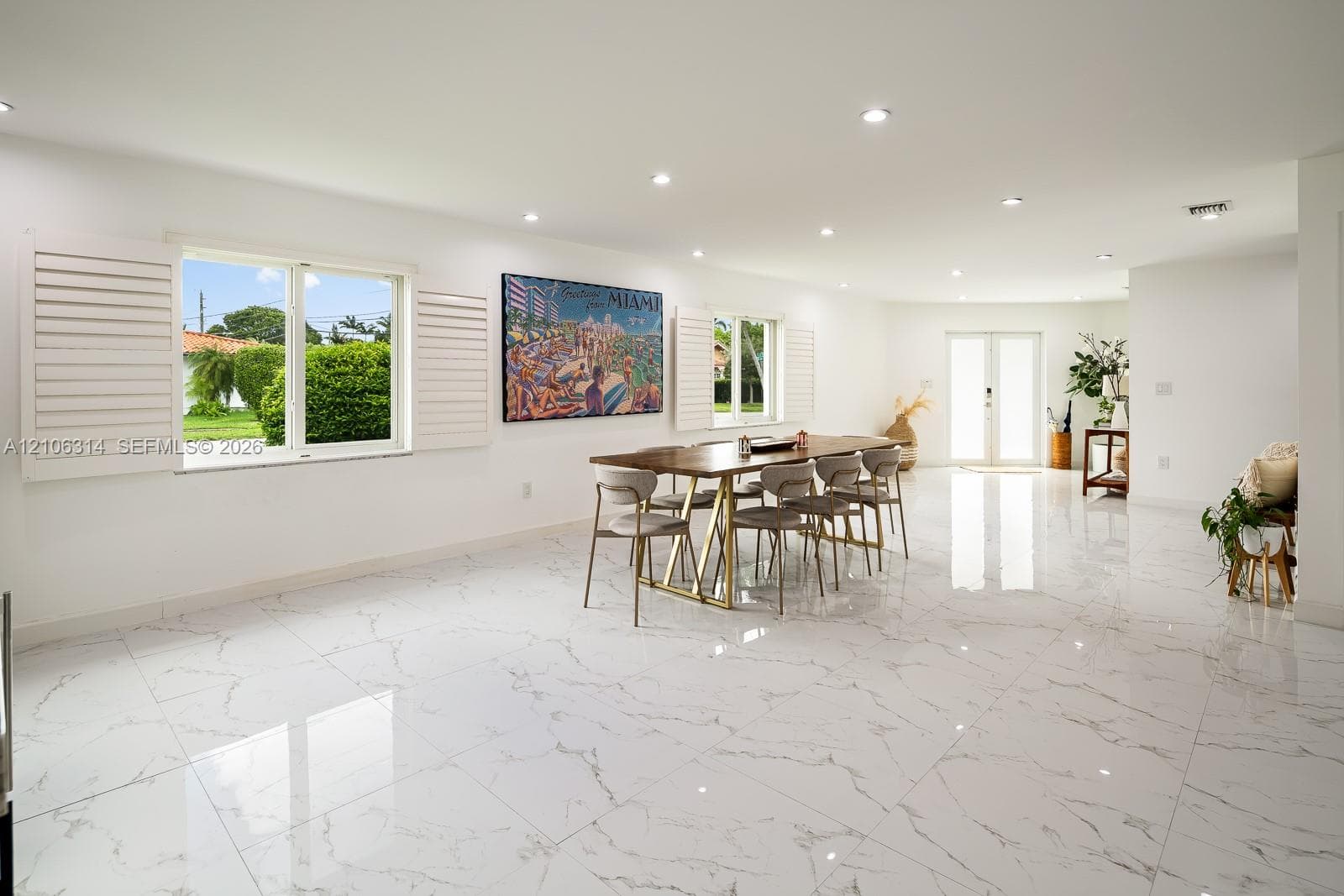 Large-format stone-finish tile flooring, recessed lighting, white louvered plantation shutters, and glass-paneled double-entry doors