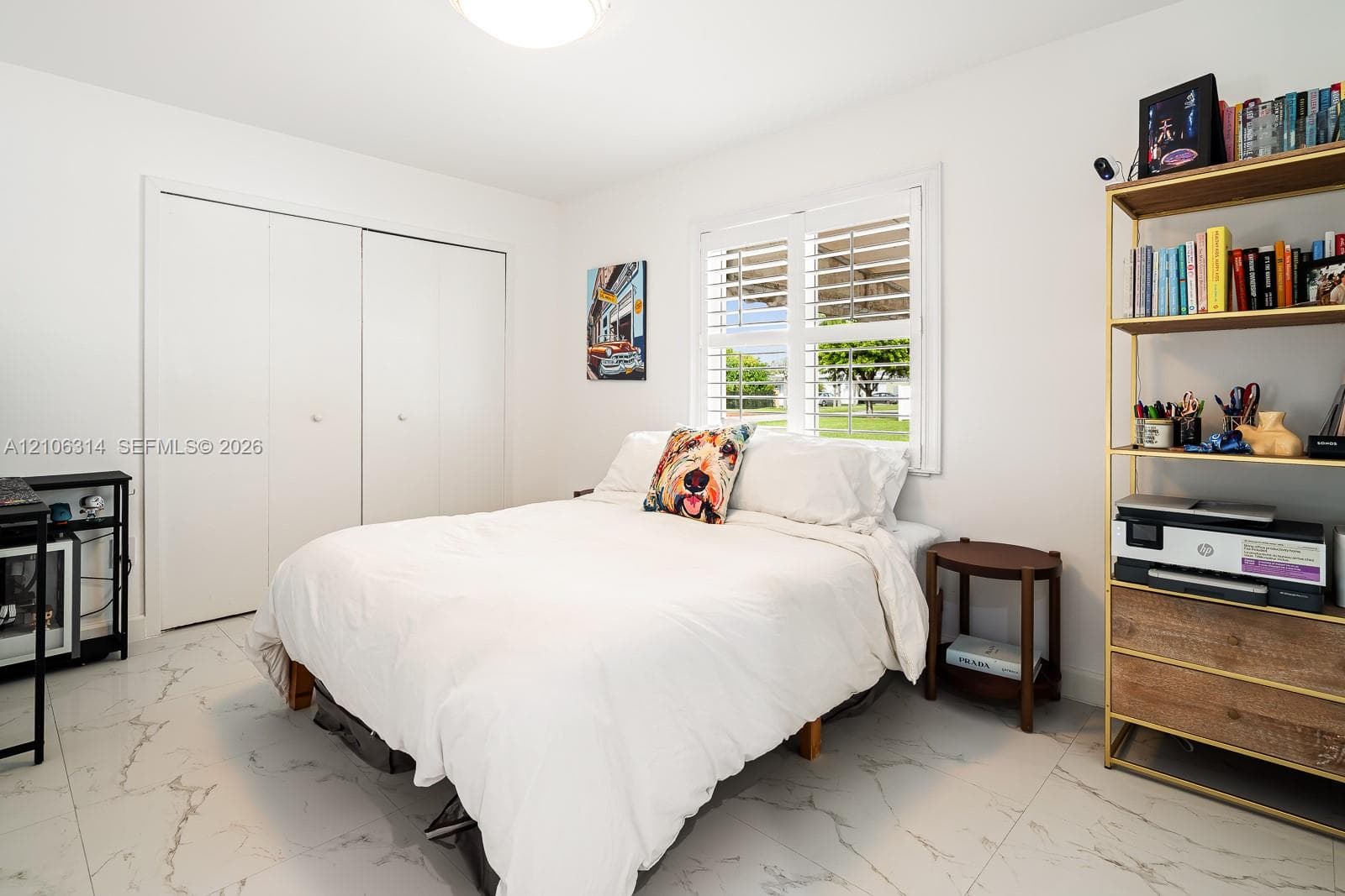 Light-filled room featuring large-format stone-finish tile flooring, dual-door floor-to-ceiling closet, and window outfitted with plantation shutters