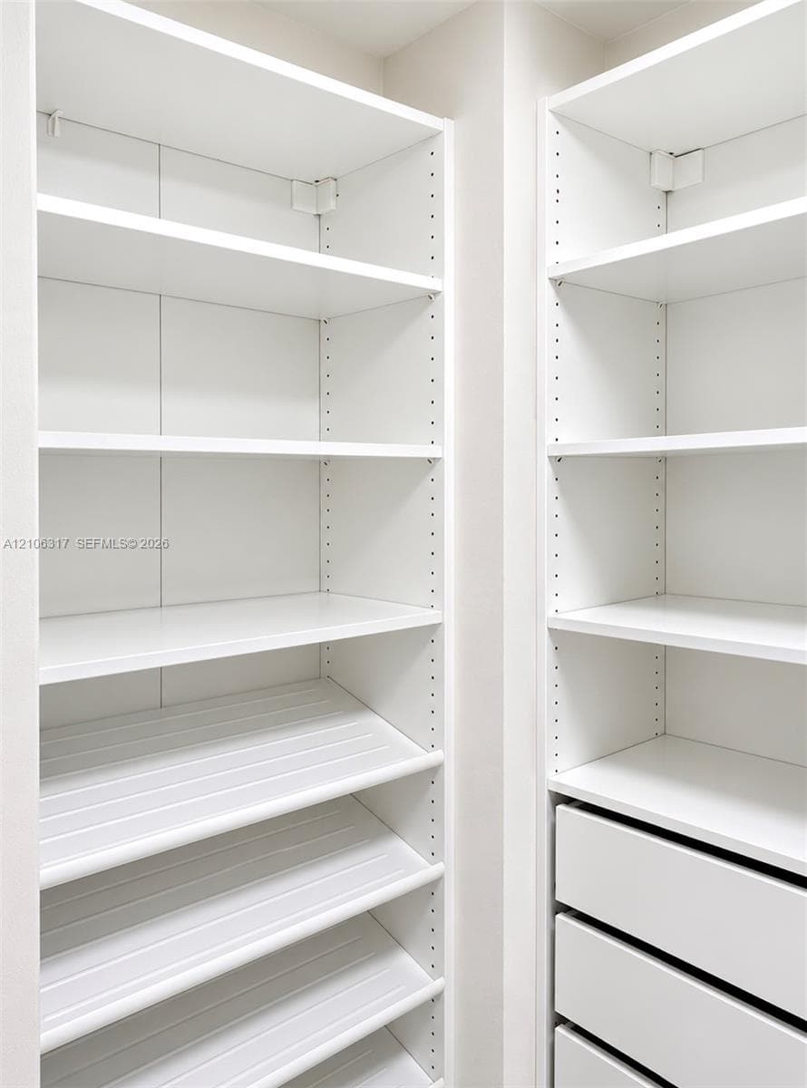 Custom white shelving system featuring adjustable heights, integrated storage drawers, and specialized angled shoe storage shelving