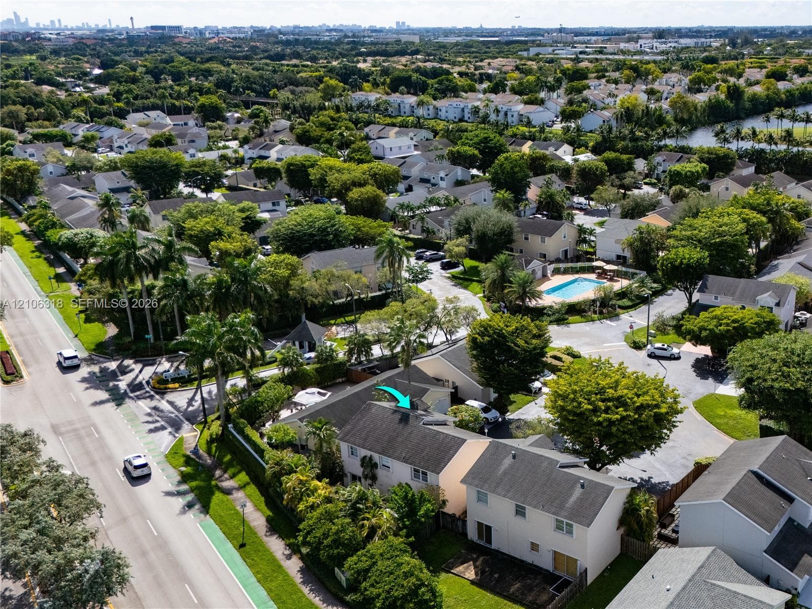 Aerial perspective of a multi-story residence featuring a shingled roof, light-toned exterior siding, mature landscaping, and an integrated private parking area