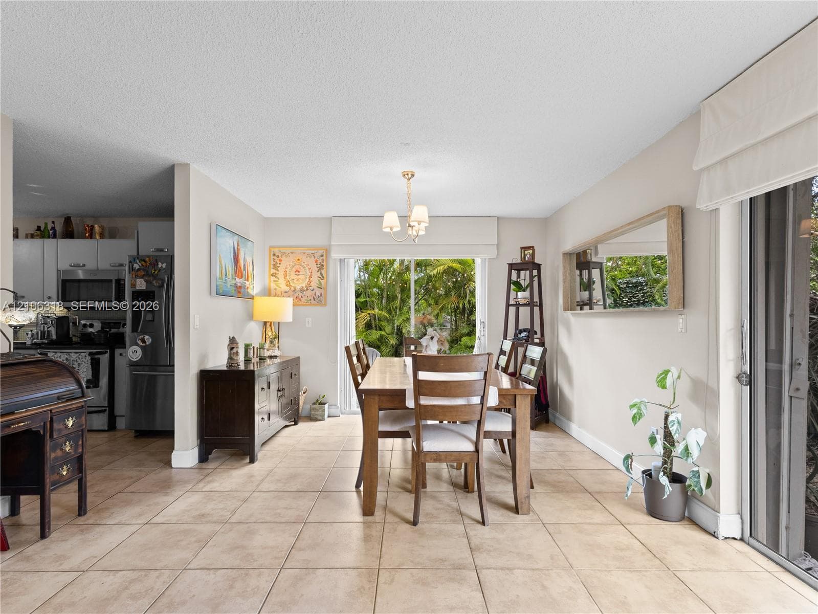 Ceramic tile flooring, neutral wall tones, multi-light chandelier, and large sliding glass doors