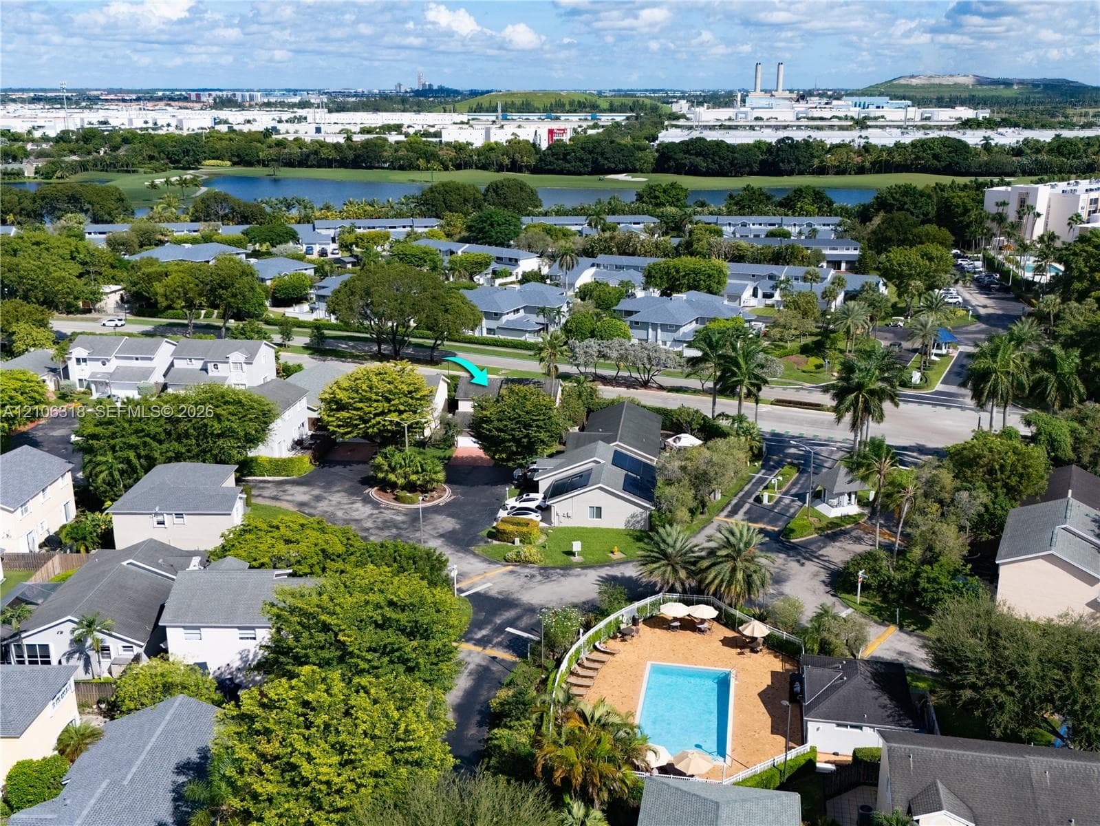 Aerial perspective featuring a residential community with mature landscaping, a swimming pool, and water features